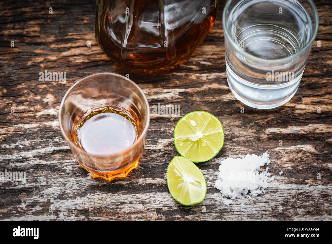 alcoholic drinks and lemon salt on rustic wood background / brandy in a  glass with alcohol bottles and water - vodka rum cognac tequila and whiskey  co Stock Photo - Alamy