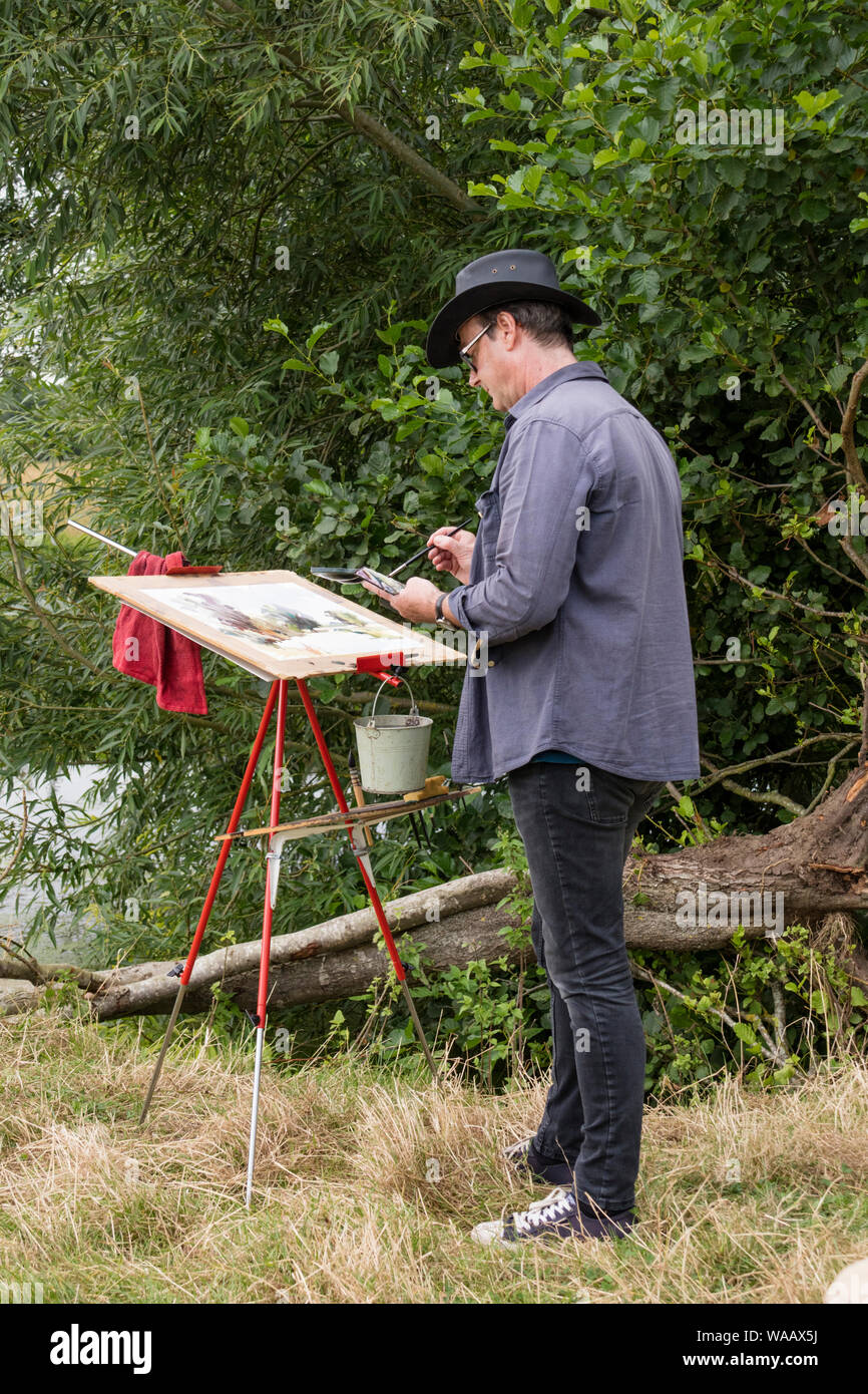Artist painting outdoors in on the River Stour, Dedham Vale, Suffolk ANOB, England, UK Stock Photo