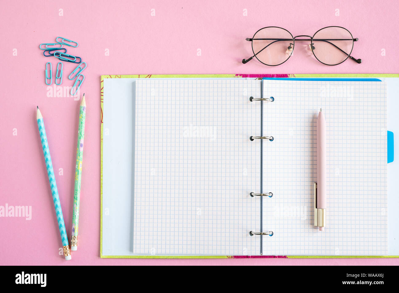 Open copybook with blank pages, pen, two pencils, clips and eyeglasses Stock Photo