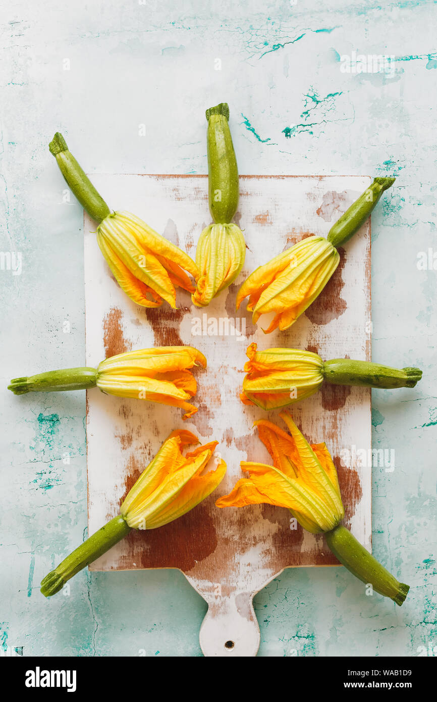 Courgettes with flowers on an old chopping board. Top view, blank space Stock Photo