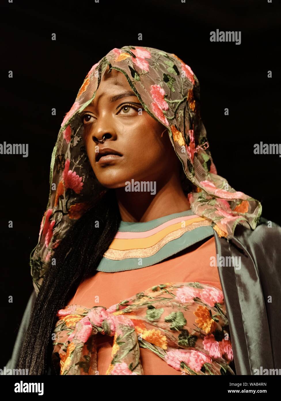 A model wearing a floral headscarf walks for designer Muhire during Africa Fashion Week in London. Stock Photo