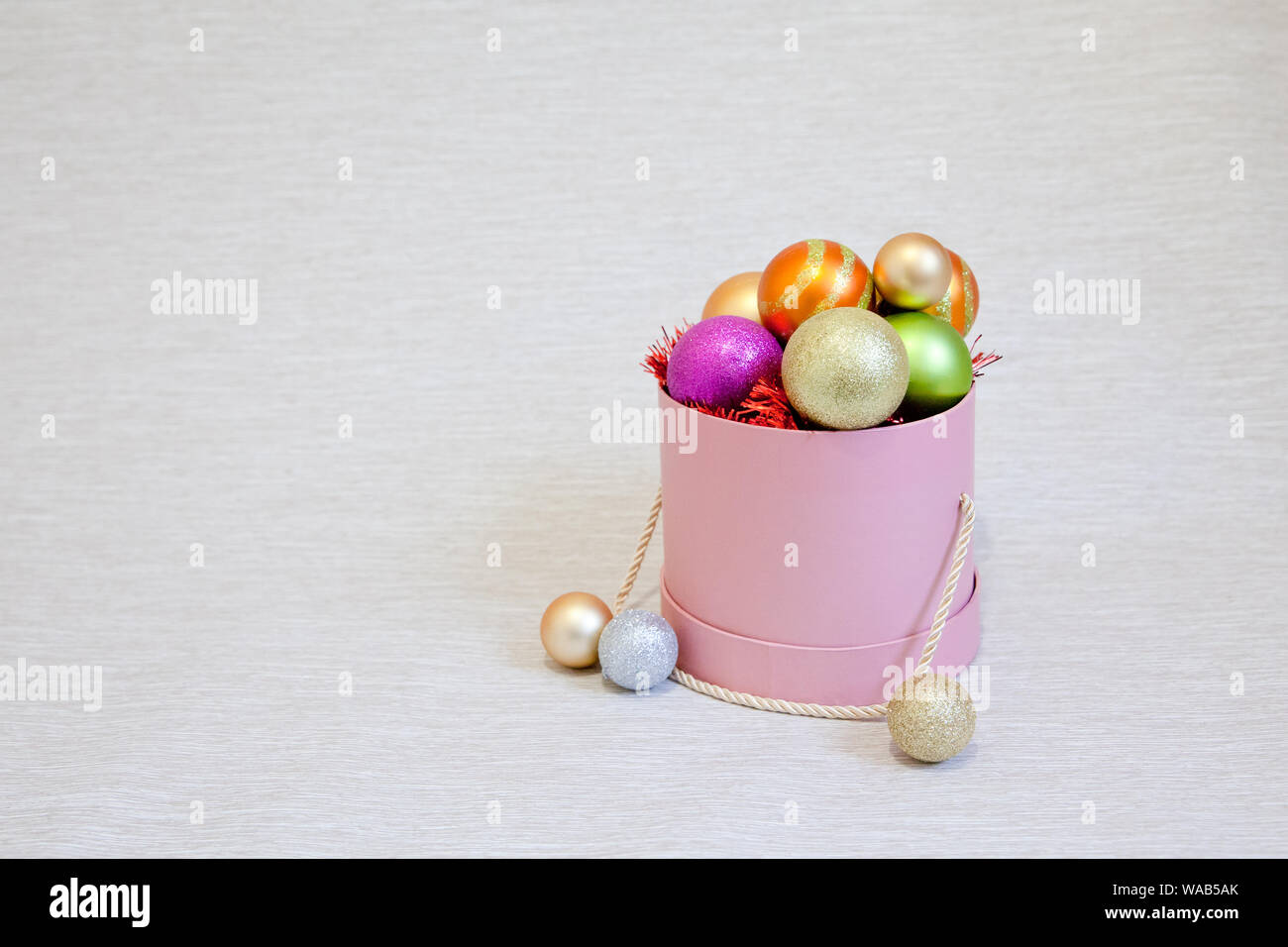 Box with Christmas balls. Pink box with christmas decorations. Colorful balloons. Stock Photo