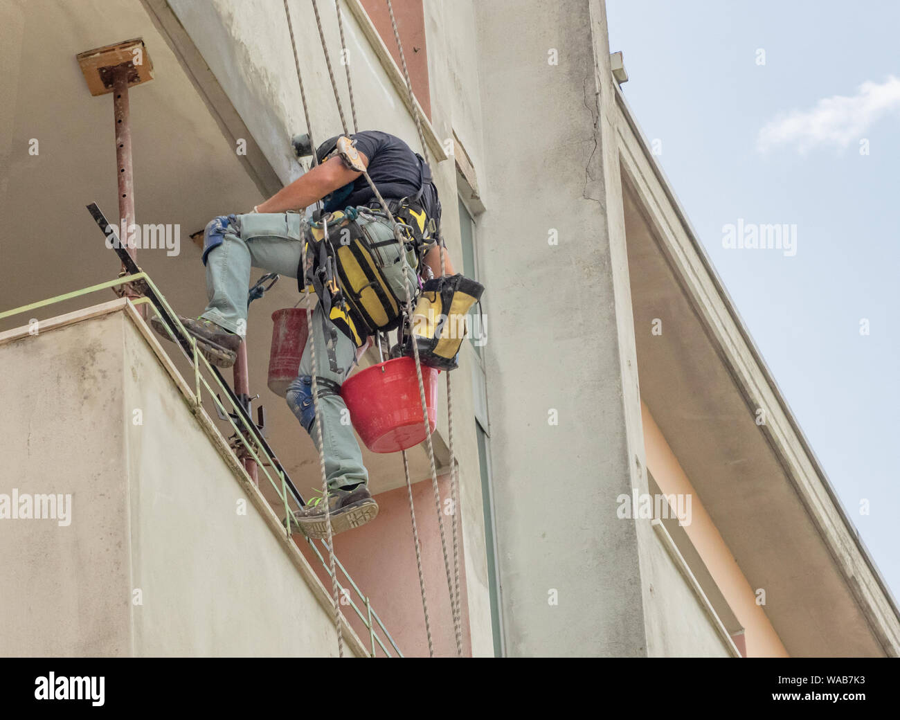 work on building facade from worker suspended with ropes Stock Photo