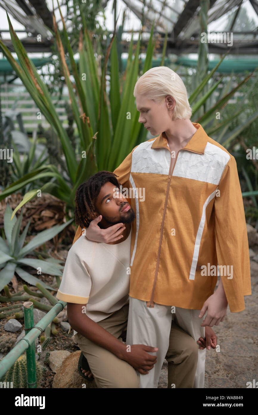 Blonde male model looking at dark-skinned man Stock Photo