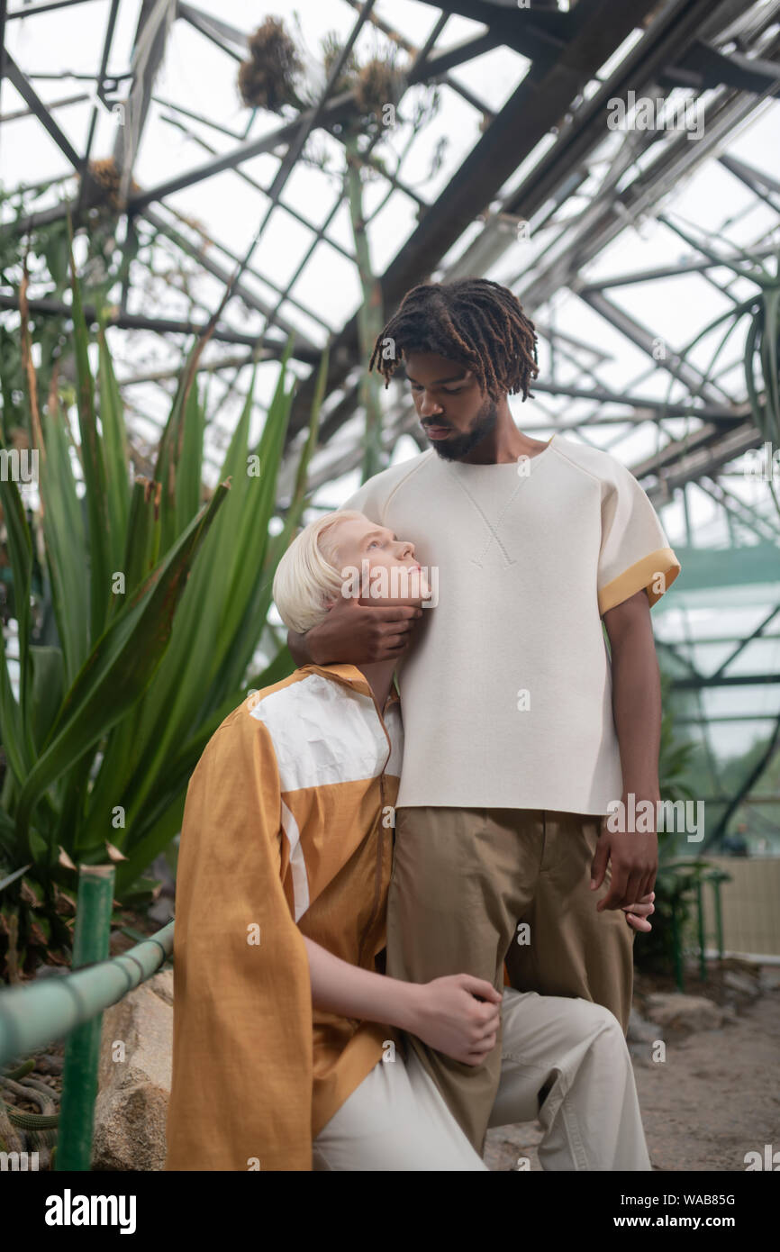 Man looking at dark-skinned men while standing in greenhouse Stock Photo