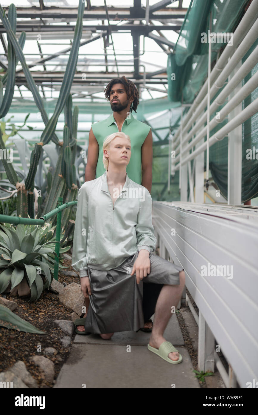 Models wearing extravagant clothing posing in greenhouse Stock Photo