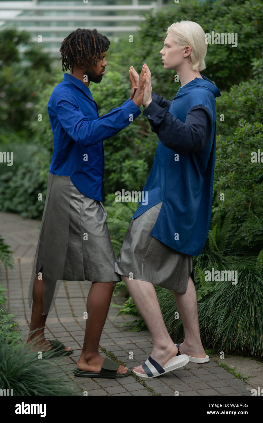 African-American and blonde-haired young men touching hands Stock Photo
