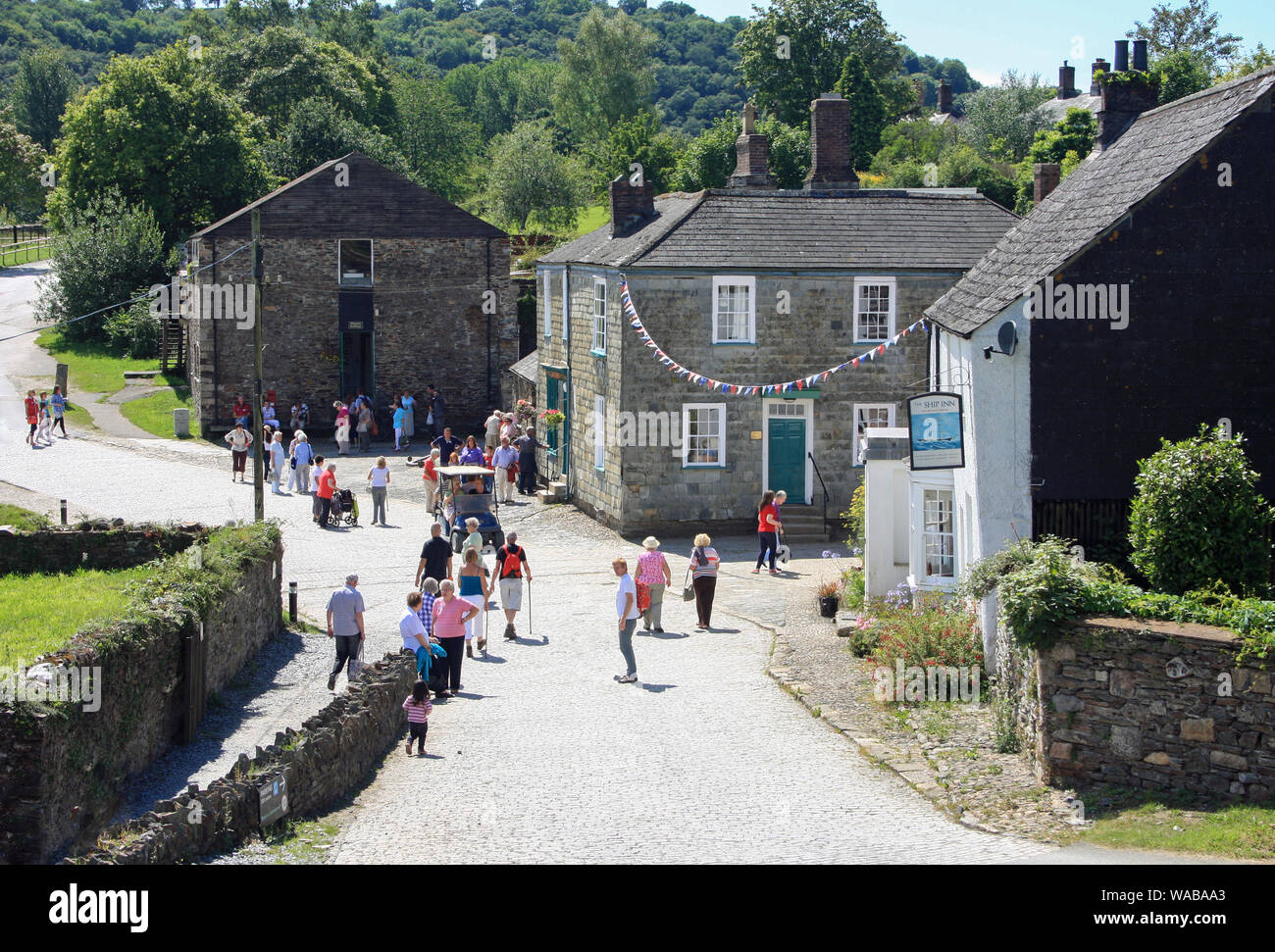 Looking over a fence to a field of grain at Visitors explore the village street at Morewellham on the Devon banks of the River Tamar Stock Photo