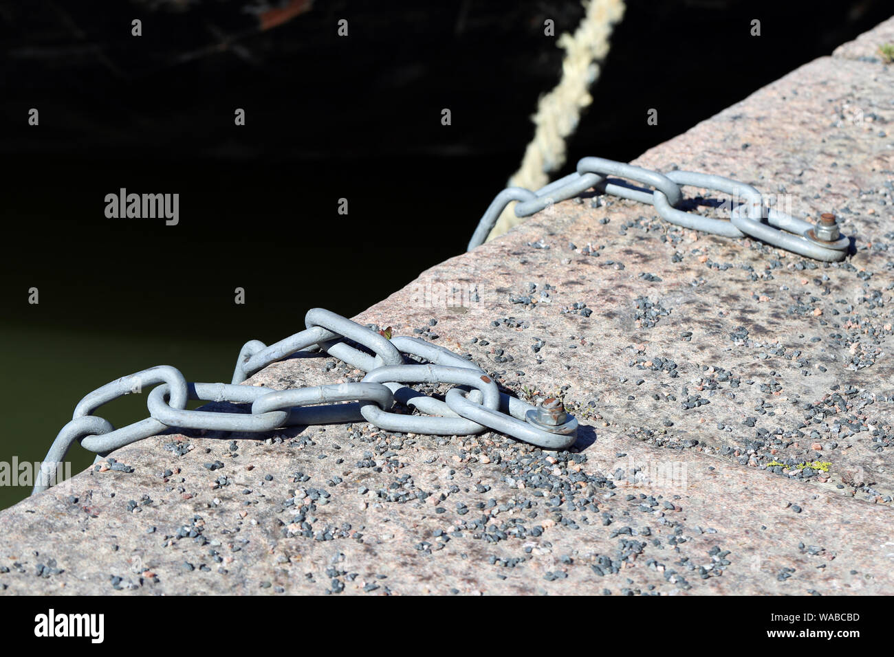 Car tires hanging with steel chains from a wall to which boats can be