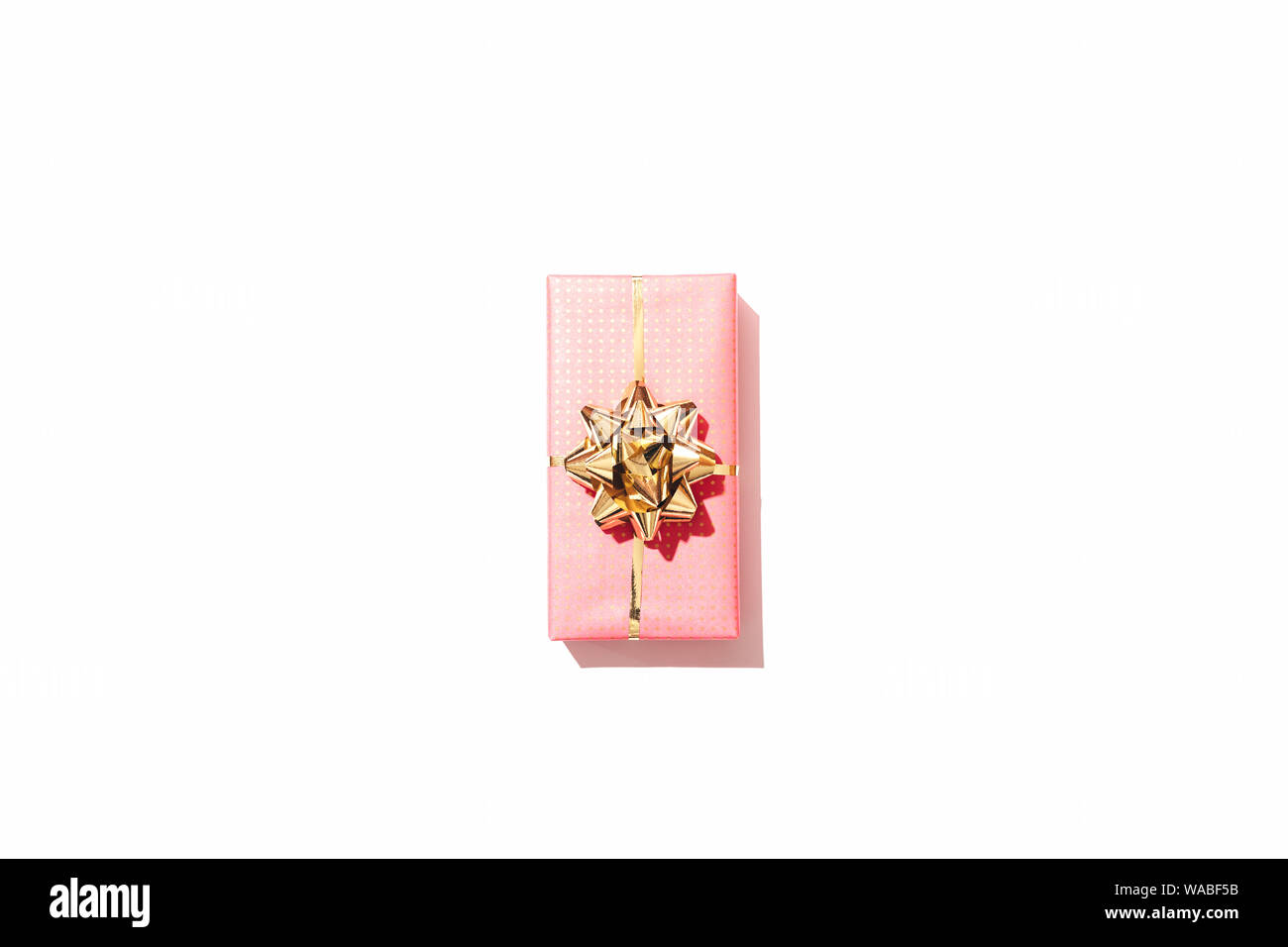 One rectangular pink gift box with golden bow in center of white ...