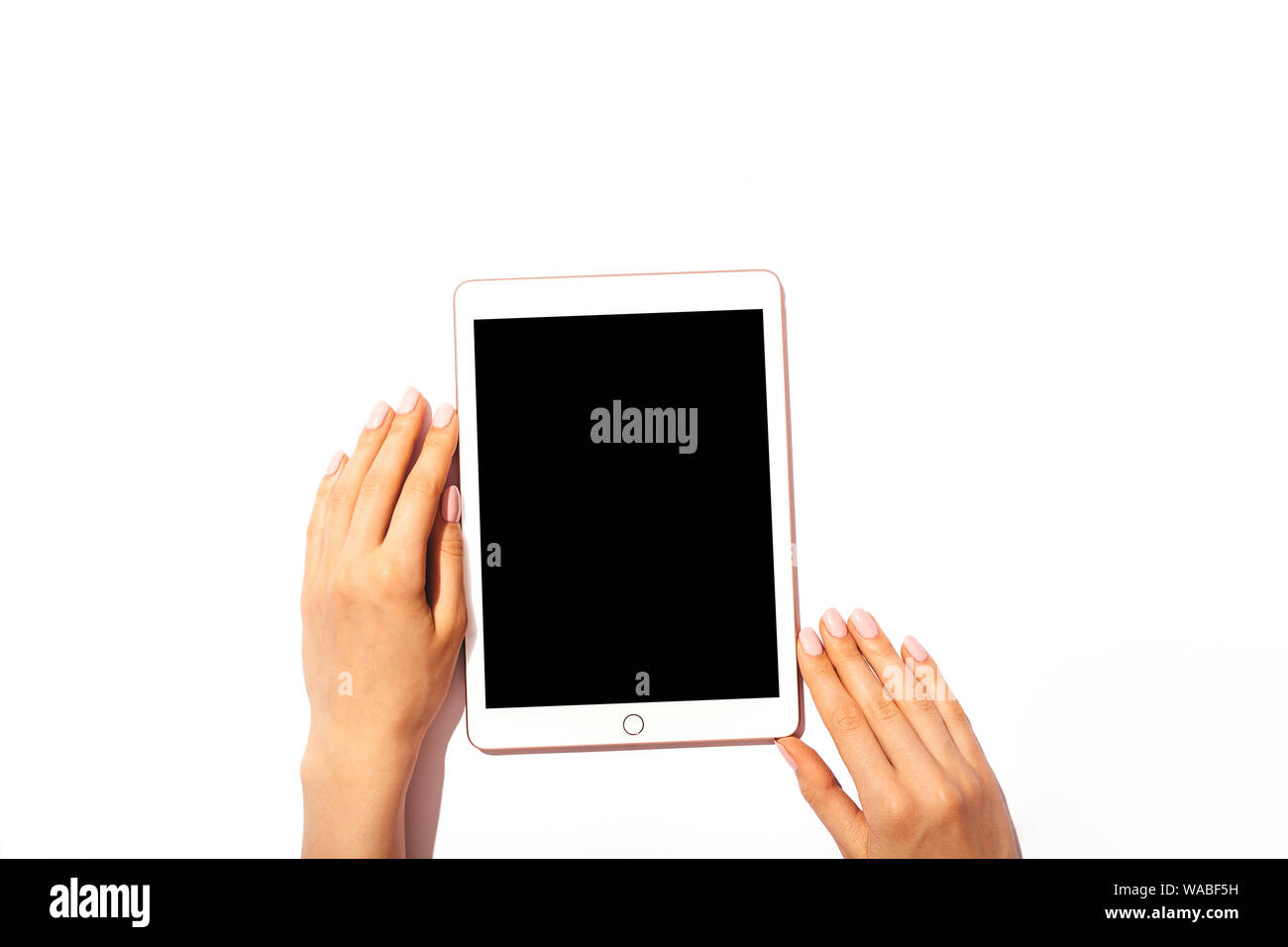 Female hands holding tablet computer with blank screen on white desktop ...
