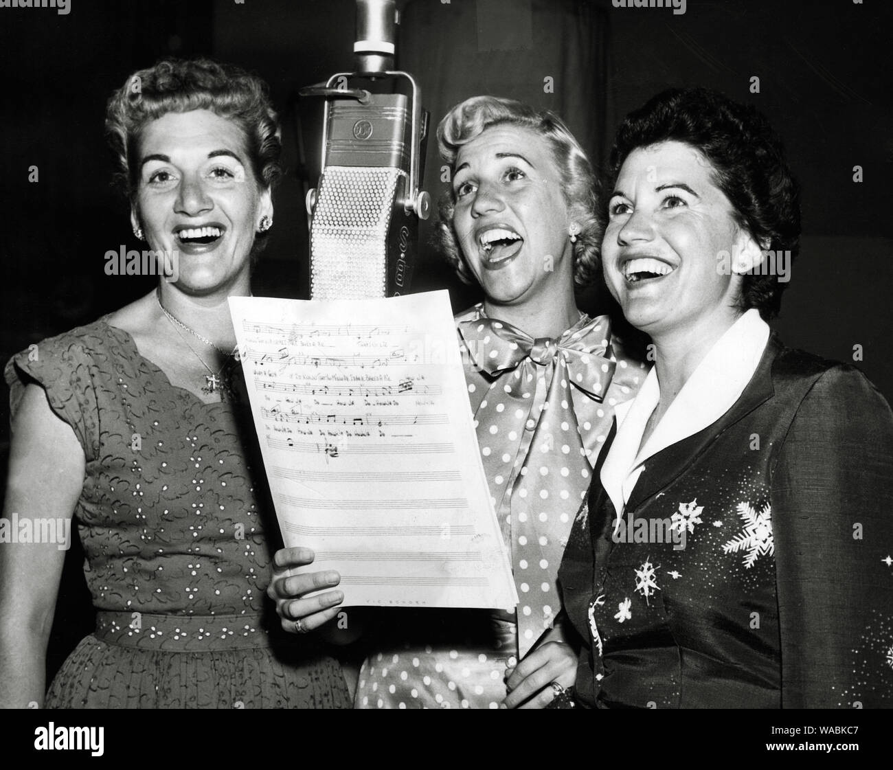 Singers and siblings LaVerne Andrews, Maxene Andrews , and Patti Andrews, of the Andrews Sisters, sing into a  microphone (circa 1948)   File Reference # 33848-334THA Stock Photo