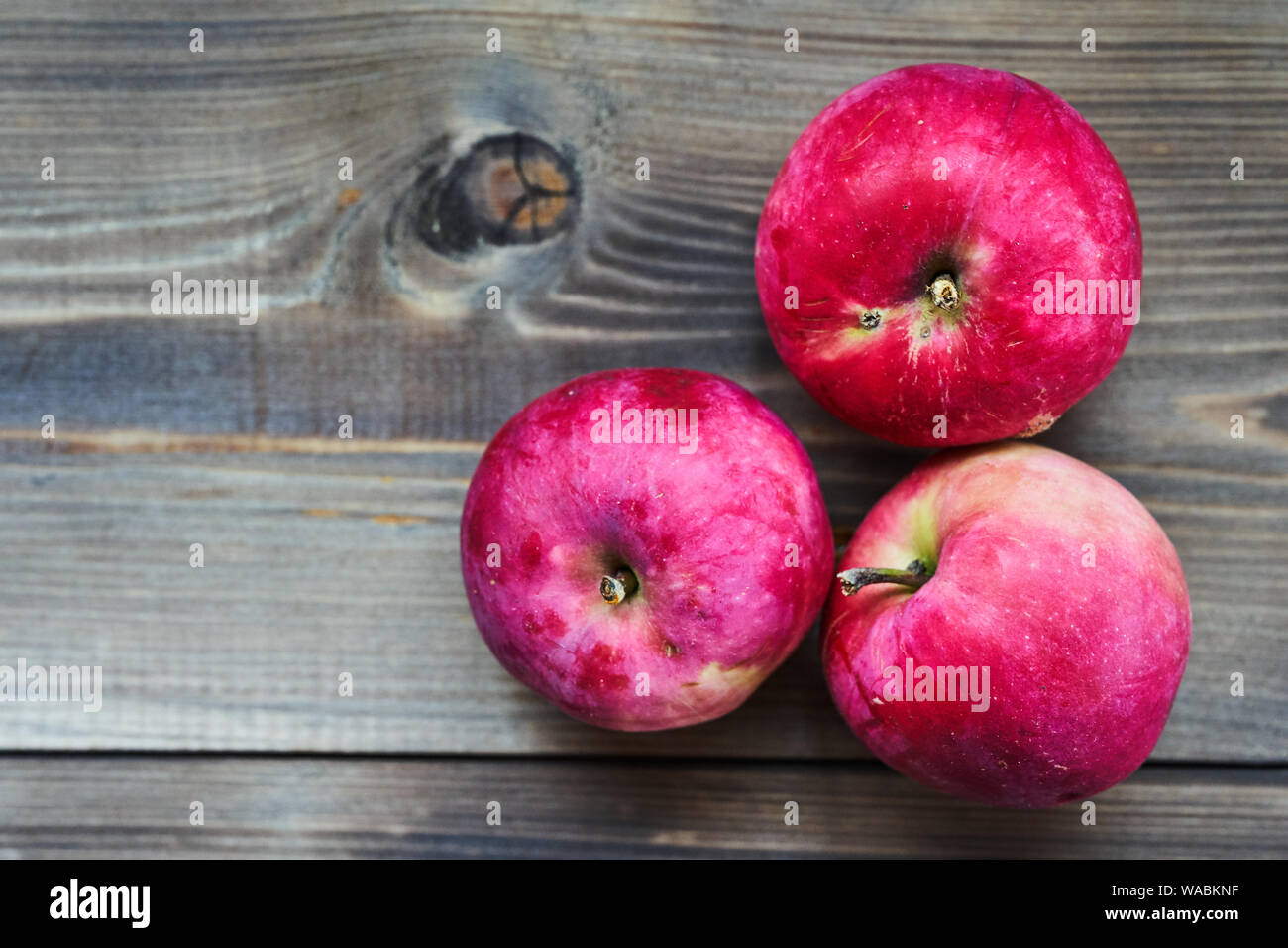 Three red ripe apples on wooden background Stock Photo - Alamy