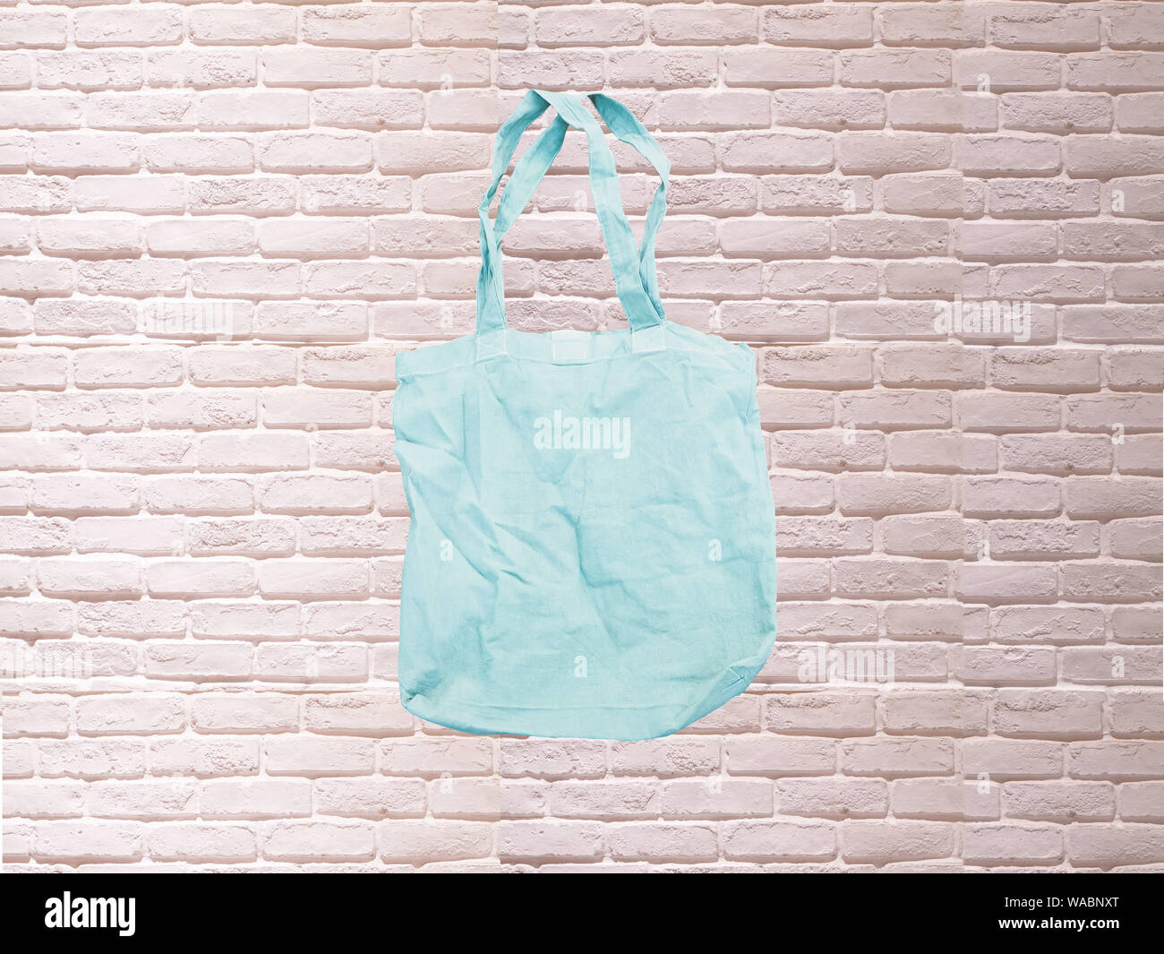 https://c8.alamy.com/comp/WABNXT/mock-up-tote-bag-eco-hipster-white-cotton-fabric-shopping-bag-in-blue-white-brick-eall-rustic-background-WABNXT.jpg