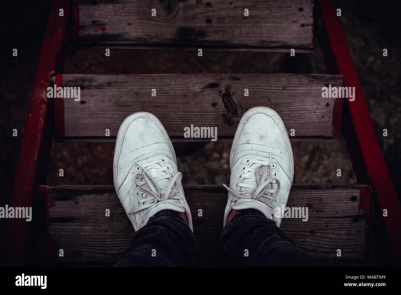 Young man feet in front of the red wood stairs down Stock Photo