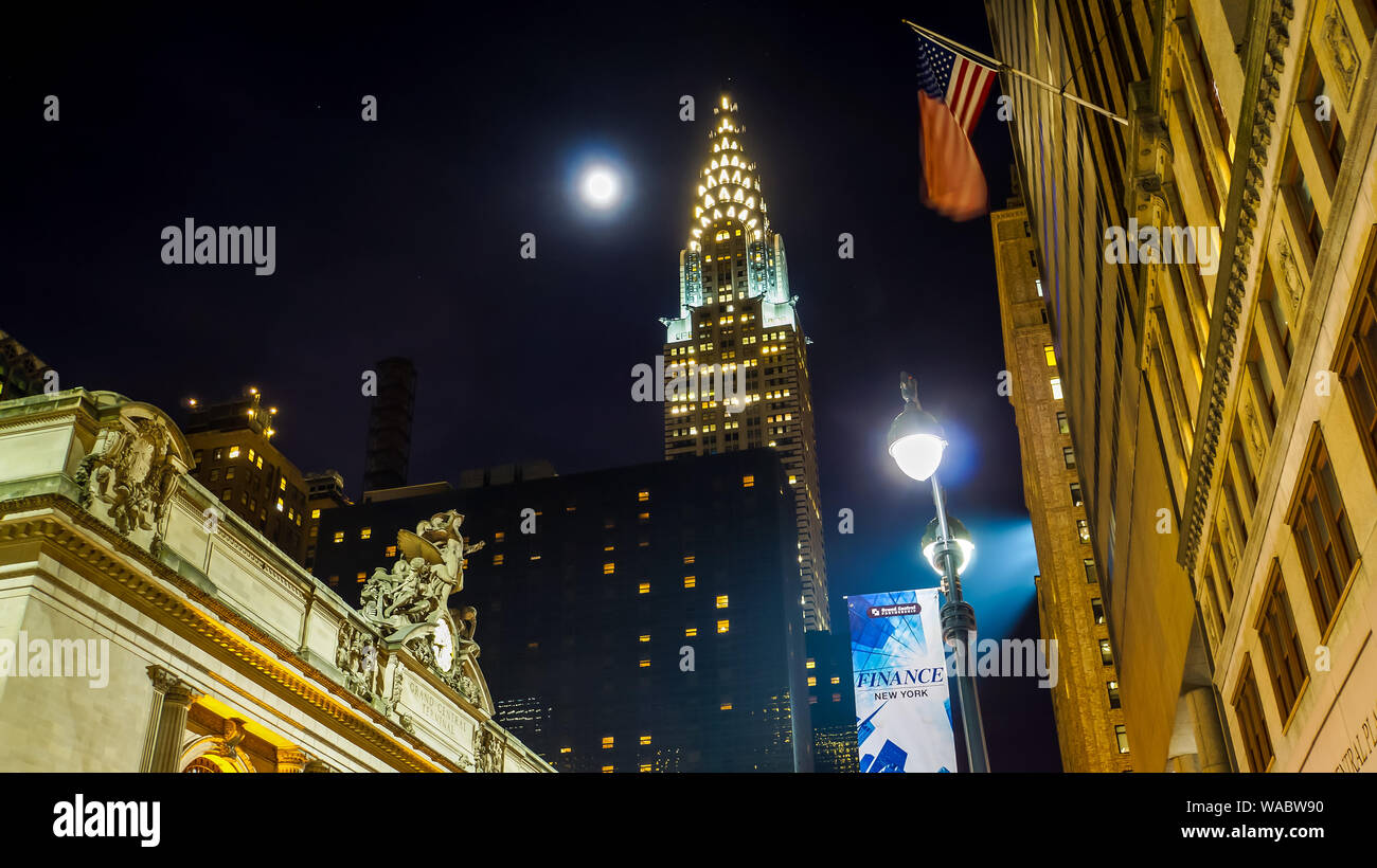 New York City, USA, January 3, 2015, Bright moonshine and starry sky over downtown manhattan shining on chrysler building at night with waving flag of Stock Photo