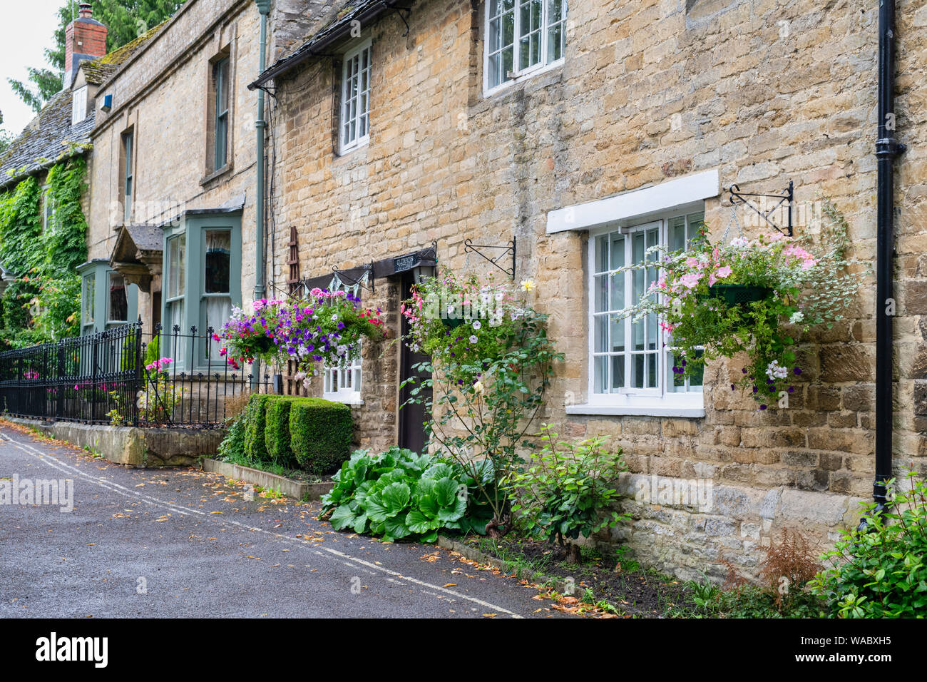 Hanging baskets and bunting outside a cottage in Burford, Cotswolds, Oxfordshire, England Stock Photo