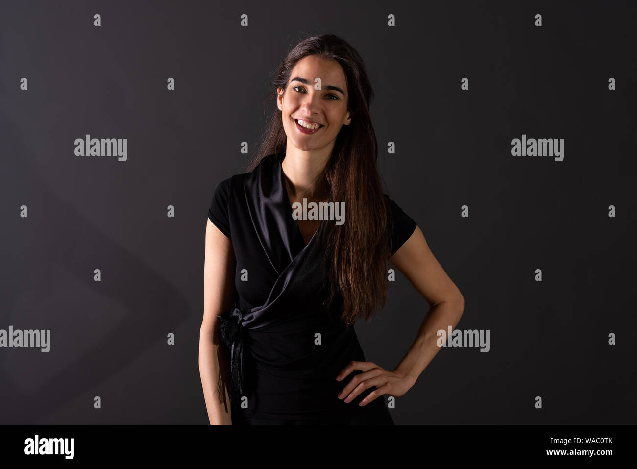A beautiful smiling young woman in an elegant black dress standing in ...