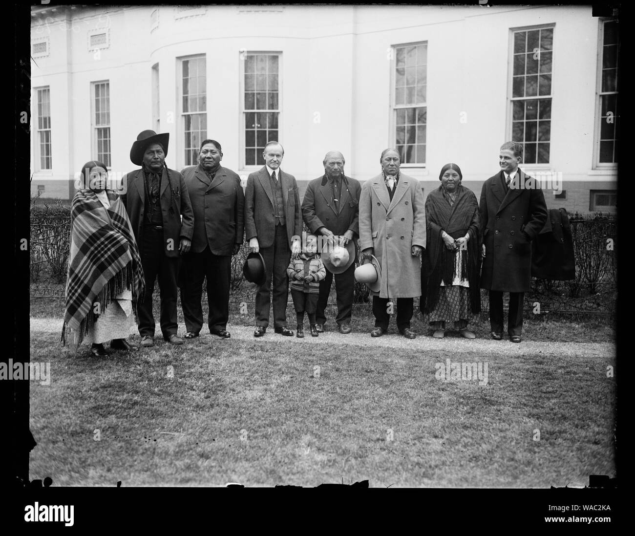Coolidge receives group of Comanche Indians at White House.; English: [Coolidge receives group of Comanche Indians at White House. [...]he Comanche tribe from the reservation [...]ma, were interesting callers on President [...] They are in Washington in the interest [...] legislation before Congress. Everett [...] Senator Pine of Oklahoma, (on extreme right) [...]skins to the president ] Stock Photo