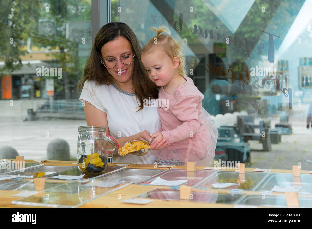 Young mother and daughter shopping in zero waste store. Raising awareness with young generations. Stock Photo