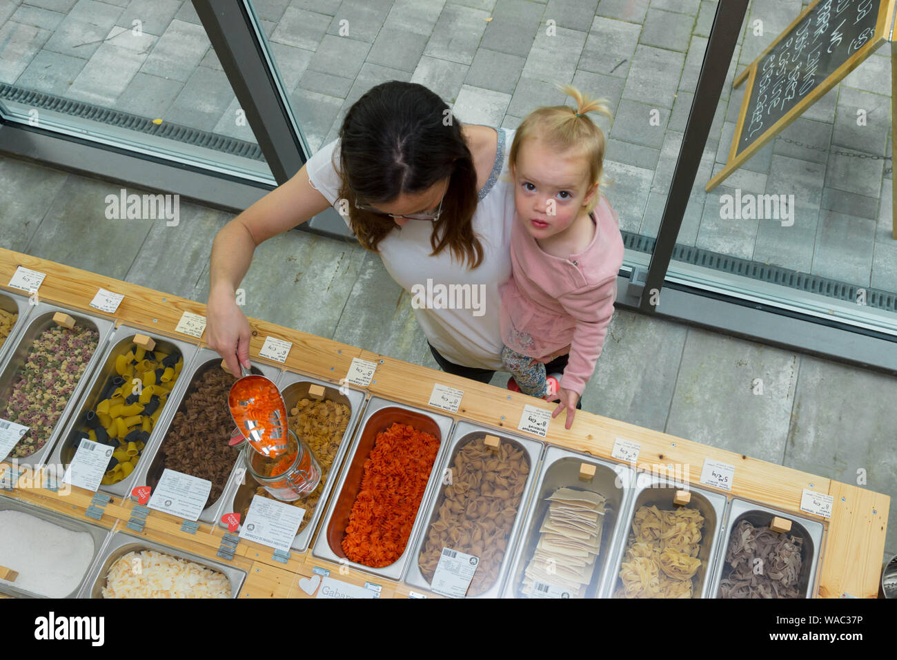 Mother and daughter shopping in zero waste store. Drop down view of bulk containers. Stock Photo