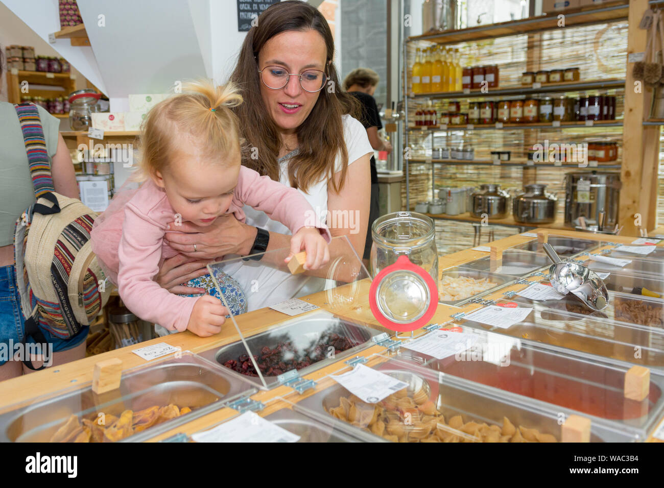 Young mother and daughter shopping in zero waste store. Raising awareness with young generations. Stock Photo