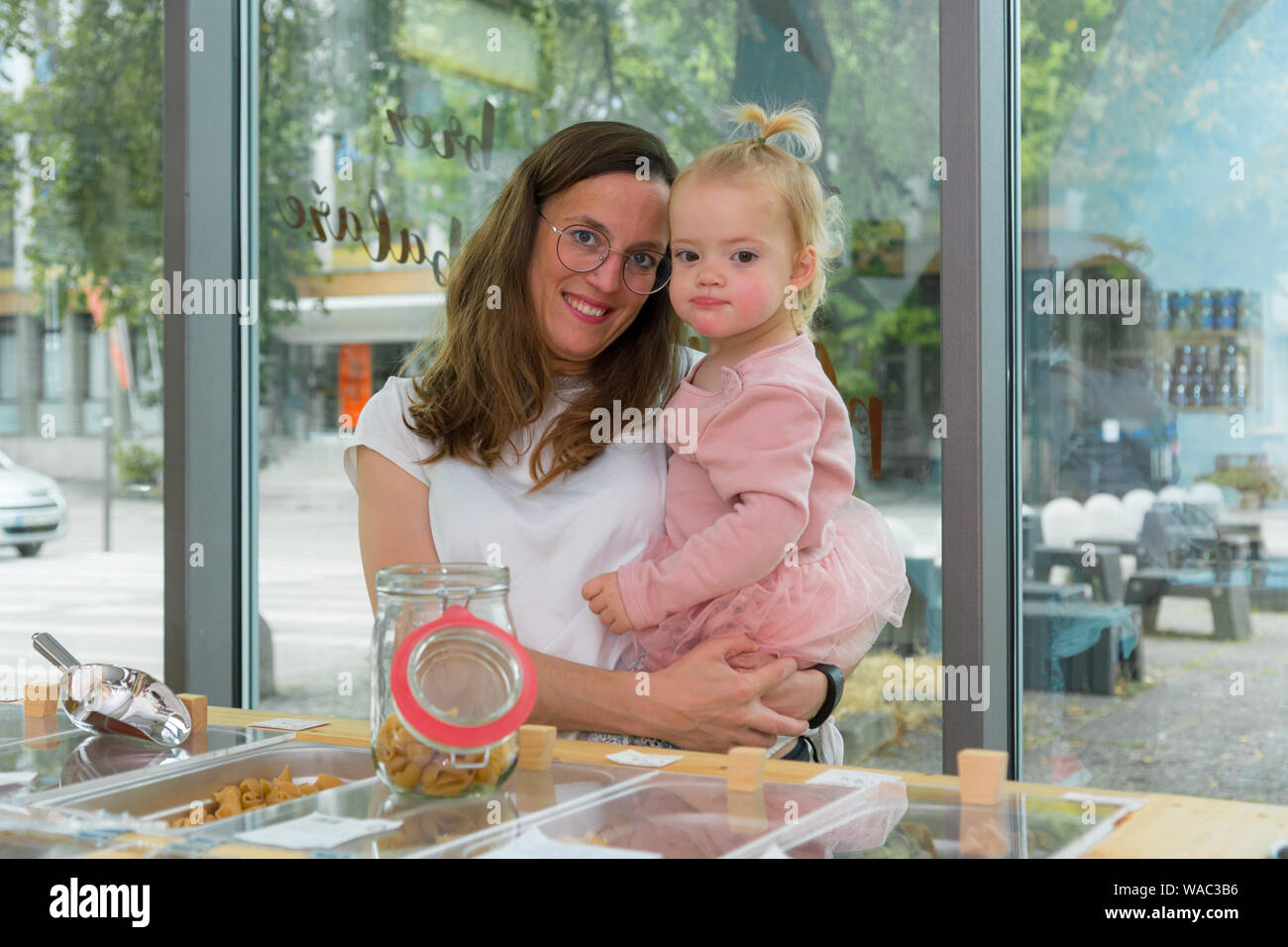 Young mother and daughter shopping in zero waste store. Raising awareness with young generations. Stock Photo