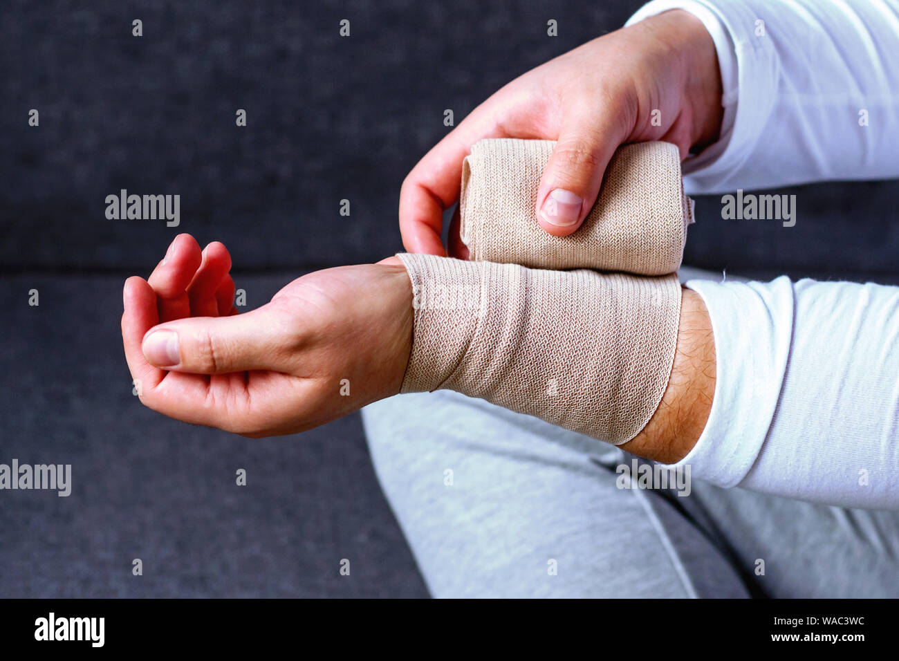A man bandages his hand with a sports bandage. Injuries and strains in