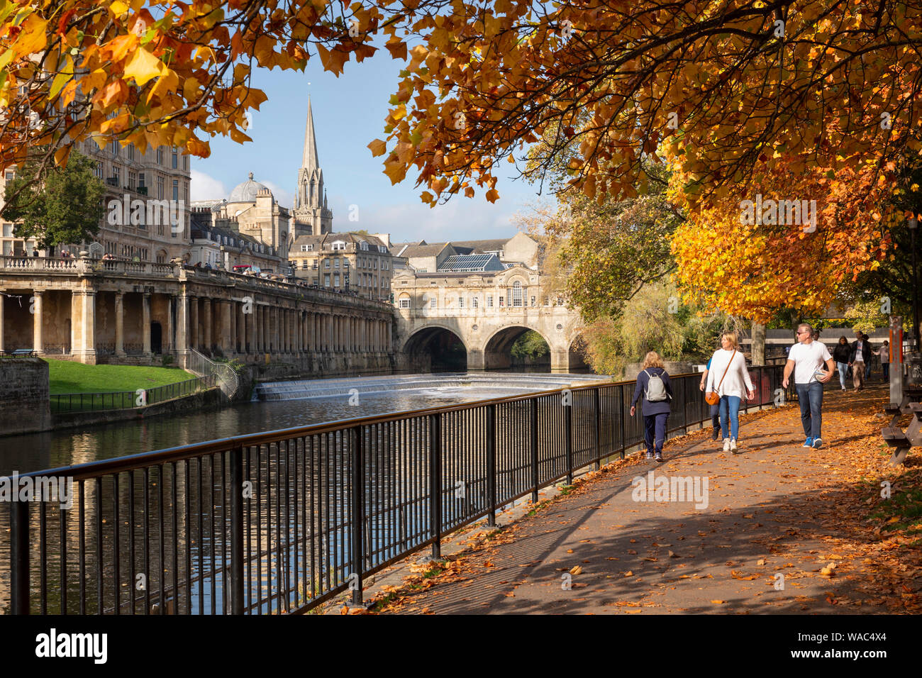 BATH, UK - October 20, 2018 : People walking beside the river Avon in the historic centre of Bath surrounded by autumnal trees. Stock Photo