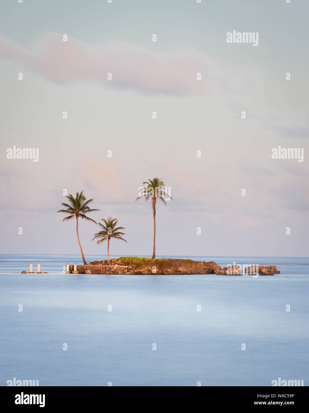 Small island with palm trees in the blue ocean taken with a long ...