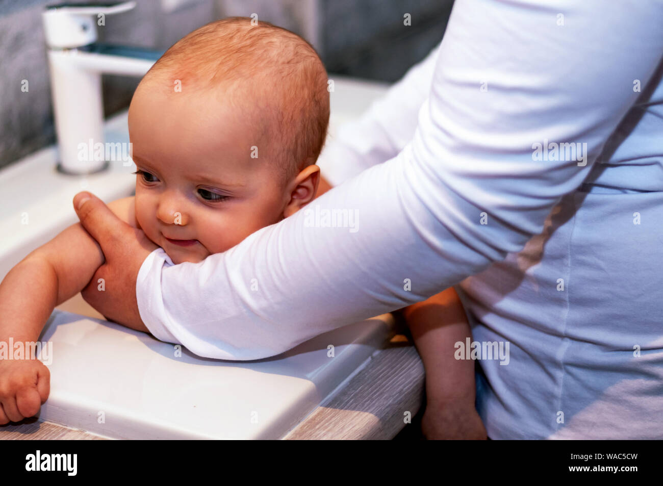 Dad washes the baby in the sink. Closeup baby. Paternity Stock Photo