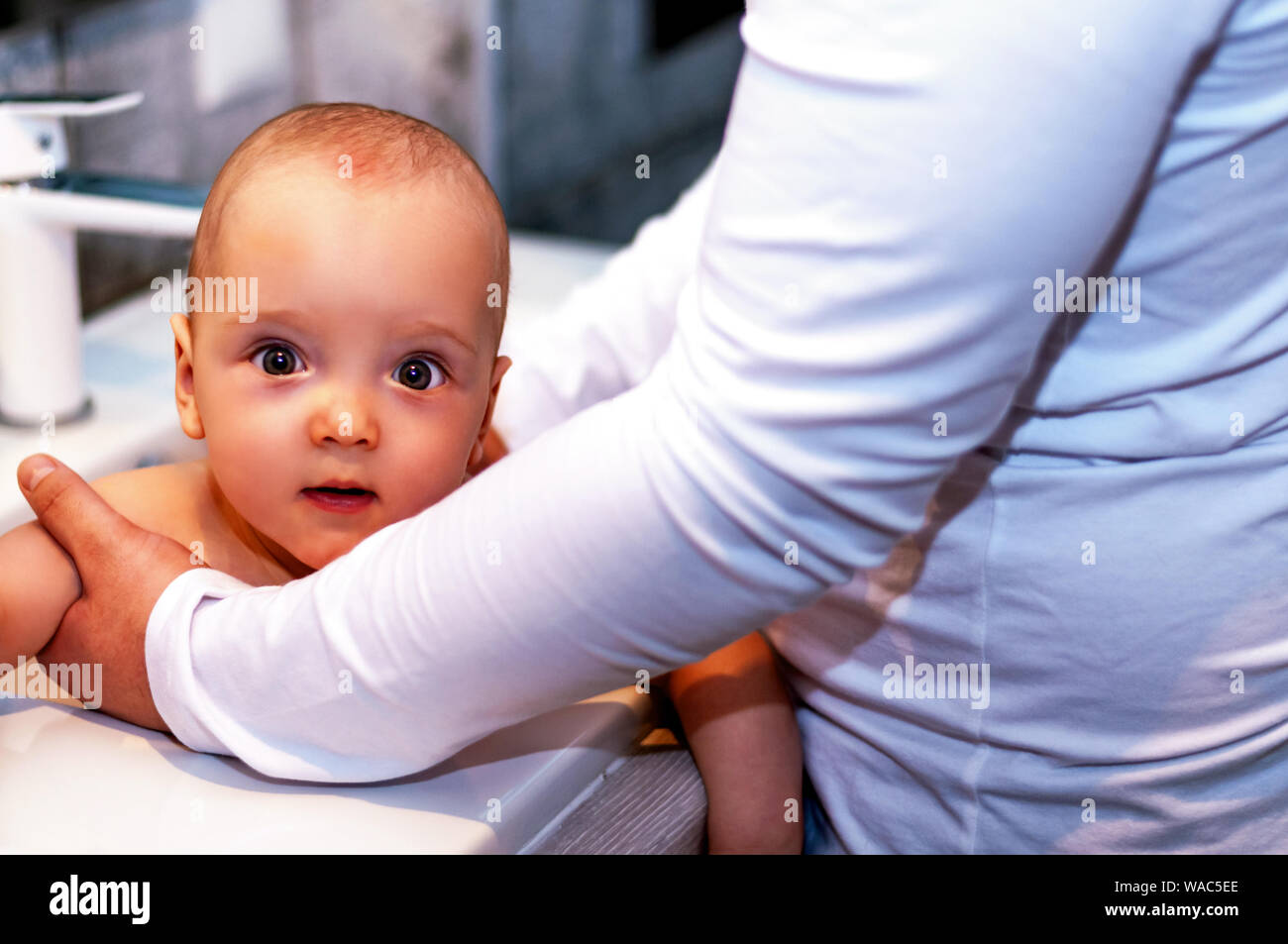 Dad washes the baby in the sink. Closeup baby. Paternity Stock Photo