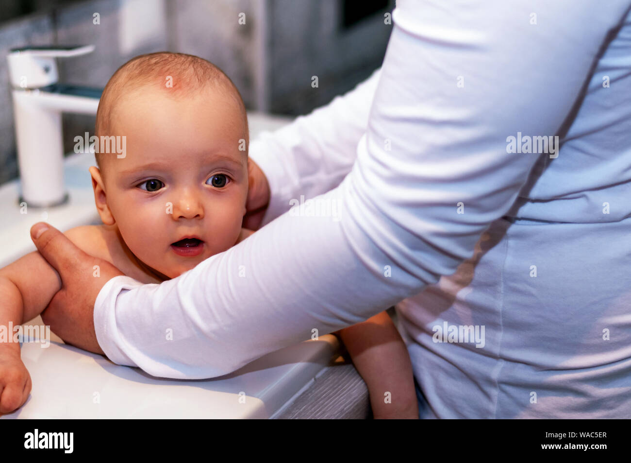 Dad washes the baby in the sink. Closeup baby. Paternity Stock Photo