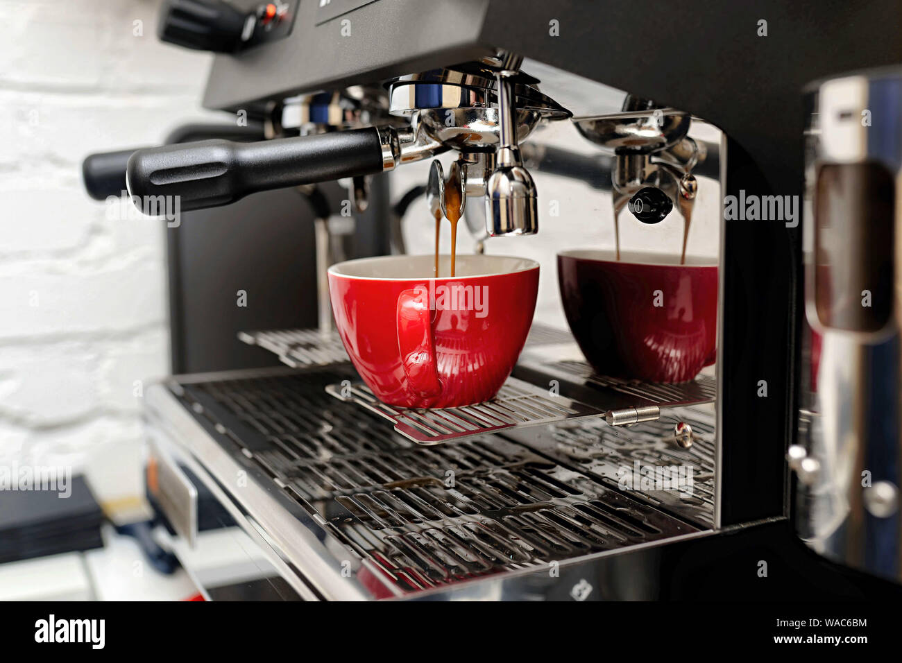 coffee machine preparing fresh coffee and pouring into red cups at