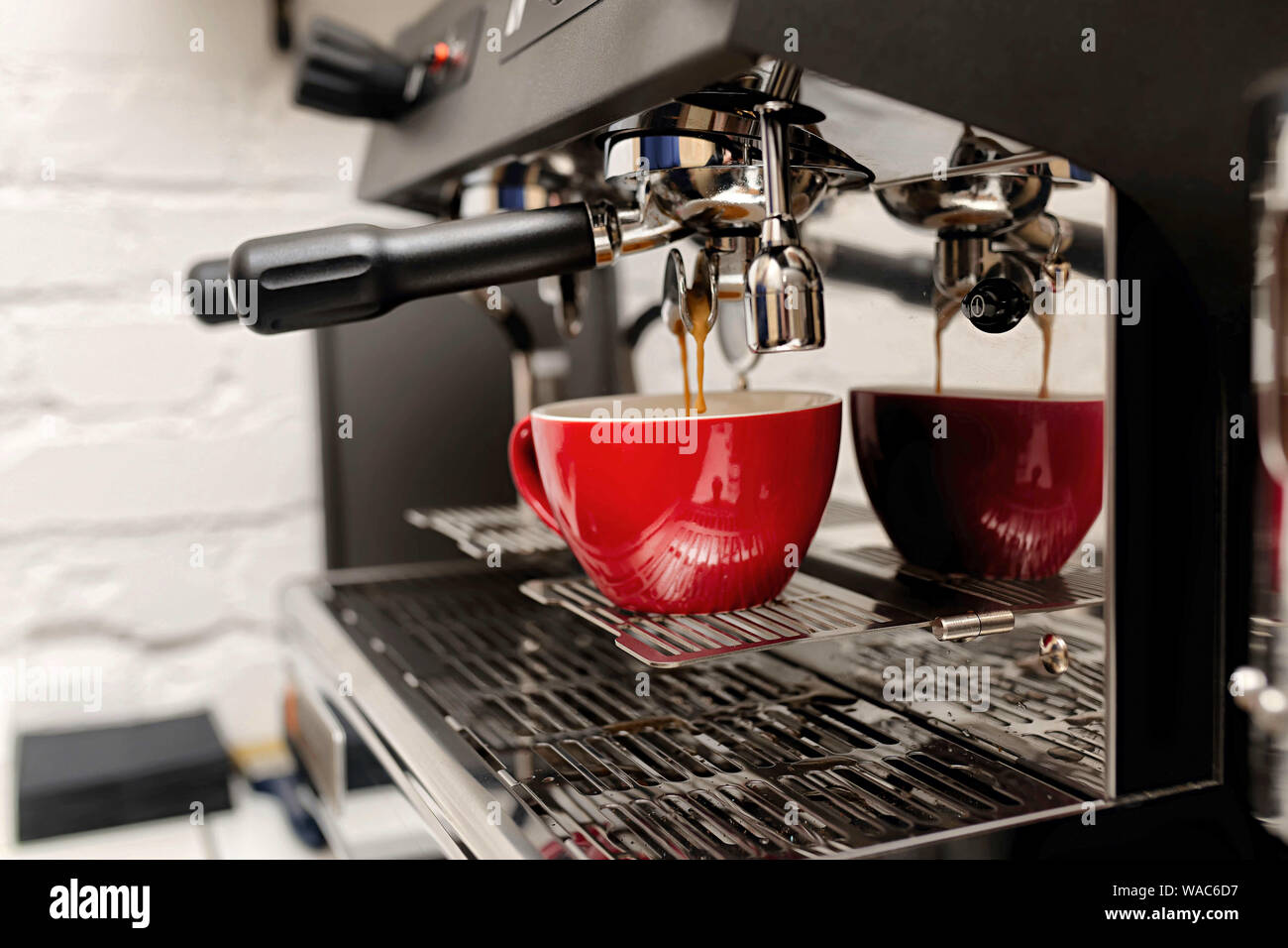 coffee machine preparing fresh coffee and pouring into red cups at