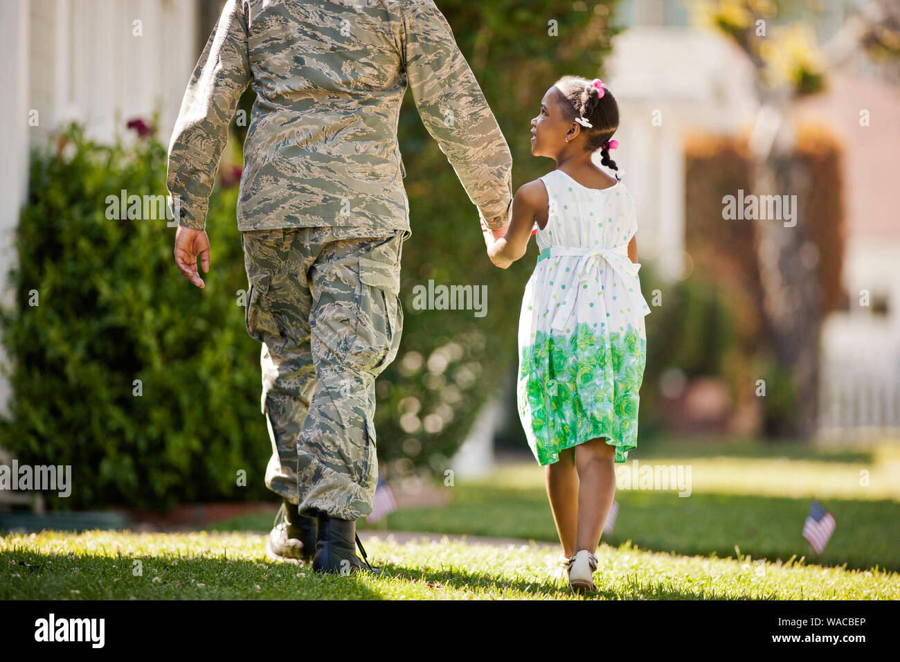 Young girl walking hand in hand with her father in their back yard ...