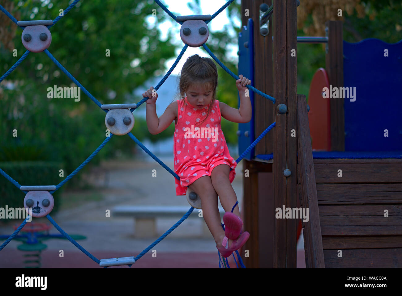 girl hanging on a net of a playground Stock Photo