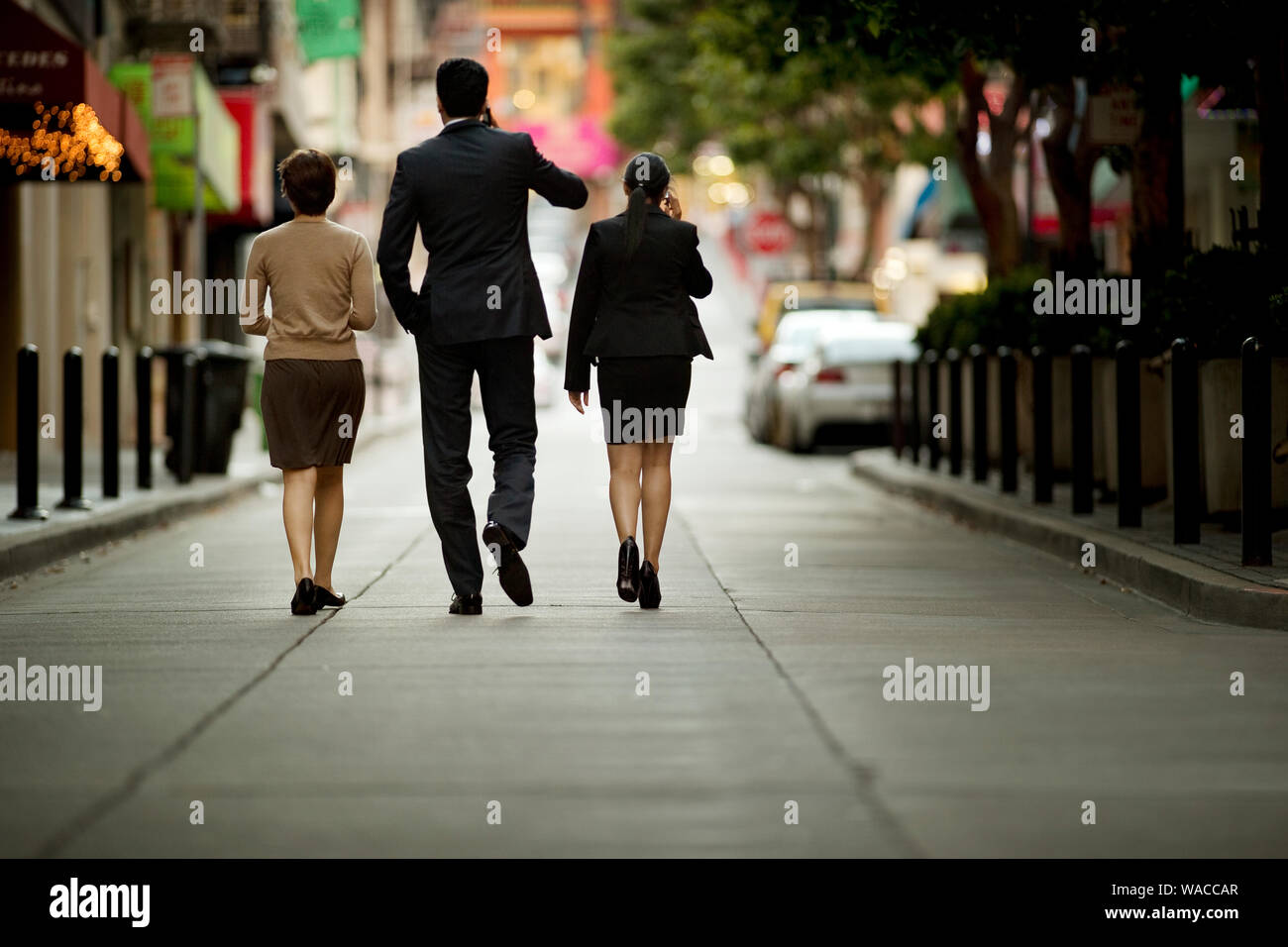 Three business colleagues talking while walking down an urban street. Stock Photo