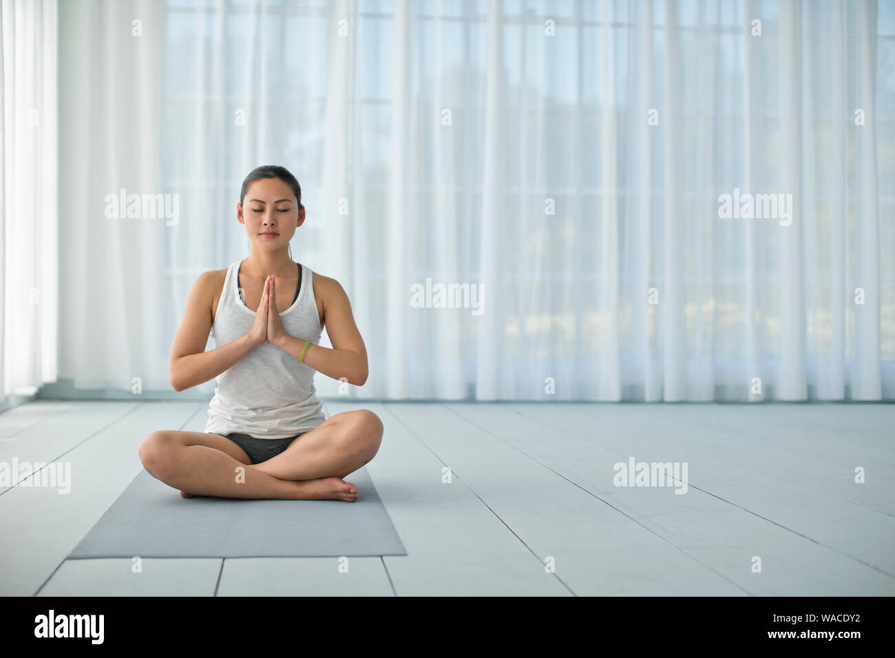 Focused young woman meditating while practicing yoga. Stock Photo