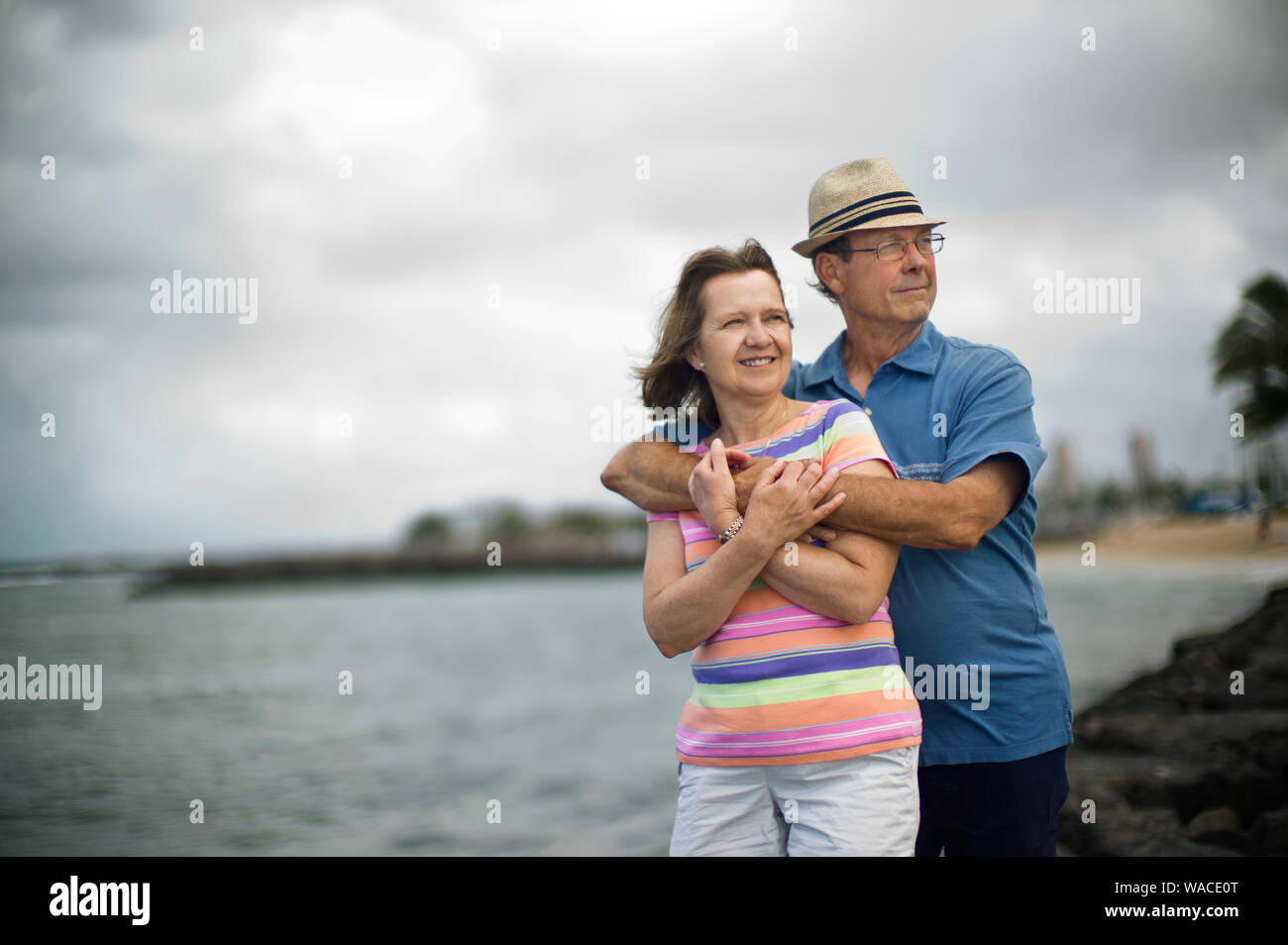 Happy mature couple standing on a beach with their arms around each other. Stock Photo