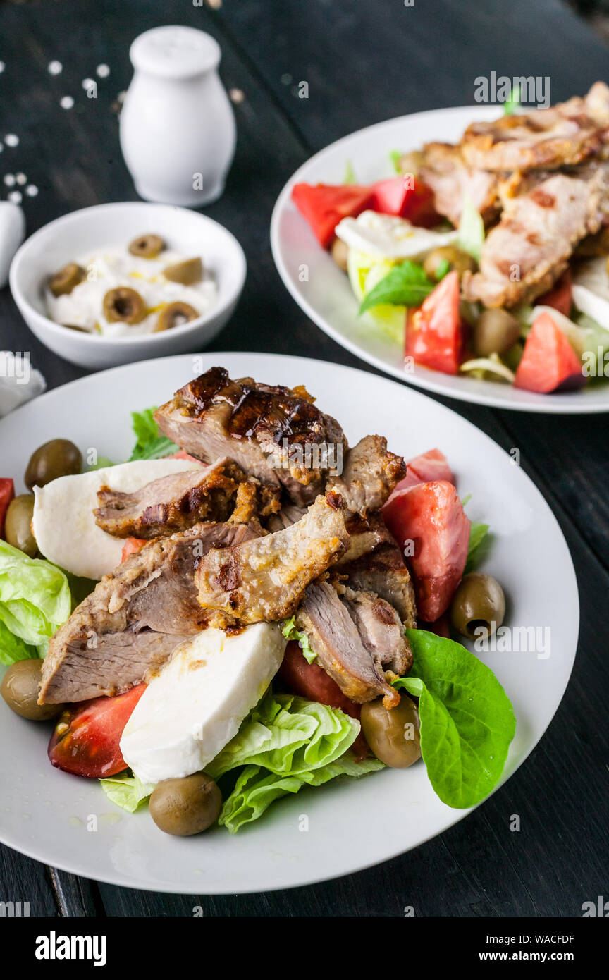 Close-up of grilled meat and salad with vegetables, mozzarella and herbs. Traditional Mediterranean Cuisine Stock Photo