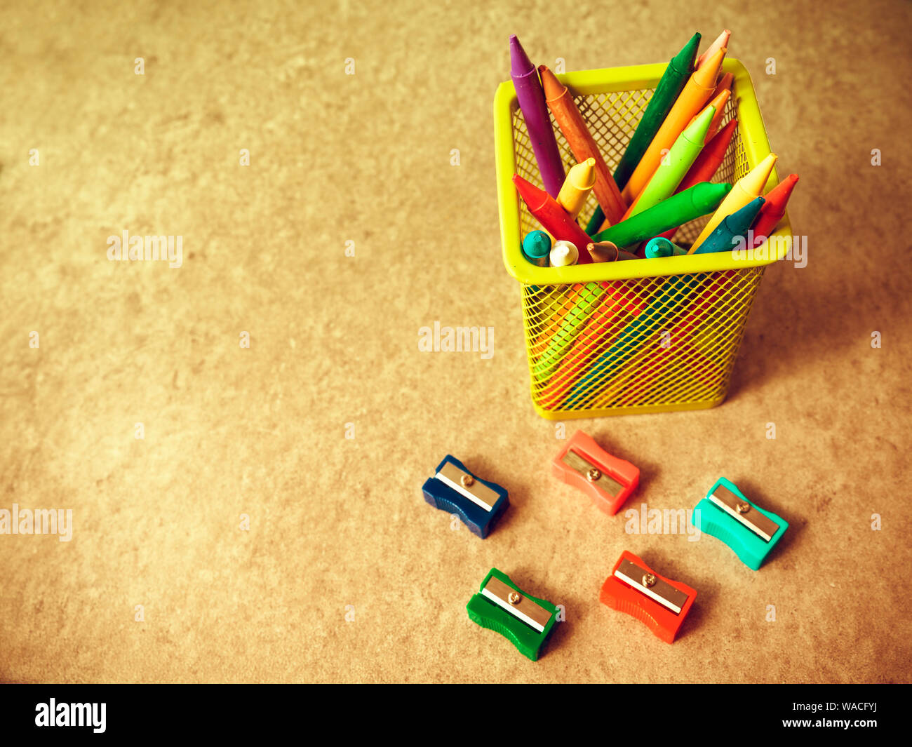 background of colored pencils to draw inside a yellow container surrounded by pencil sharpeners Stock Photo