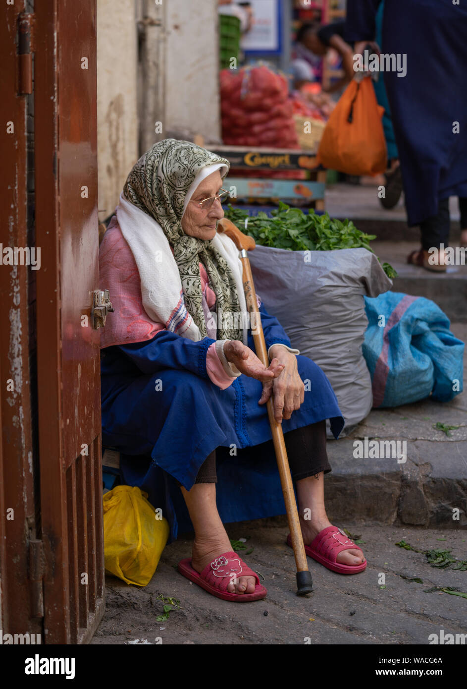 Old Moroccan woman sitting of the step and asking for money in Tangier, Morocco Stock Photo