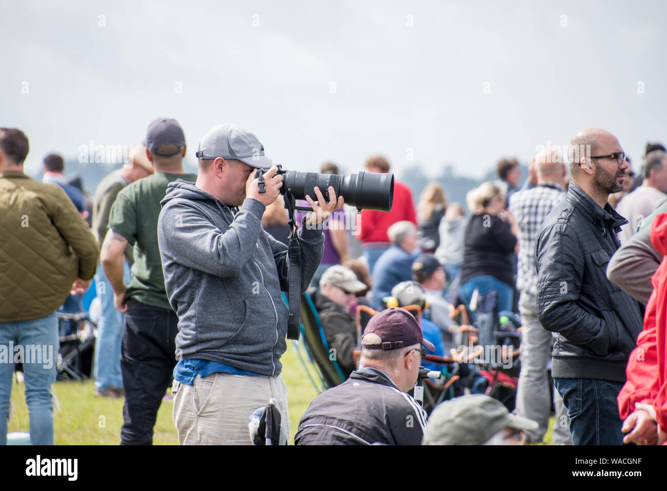 A photographer with a large lens shooting at an event with crowd around (EDITORIAL USE ONLY) Stock Photo