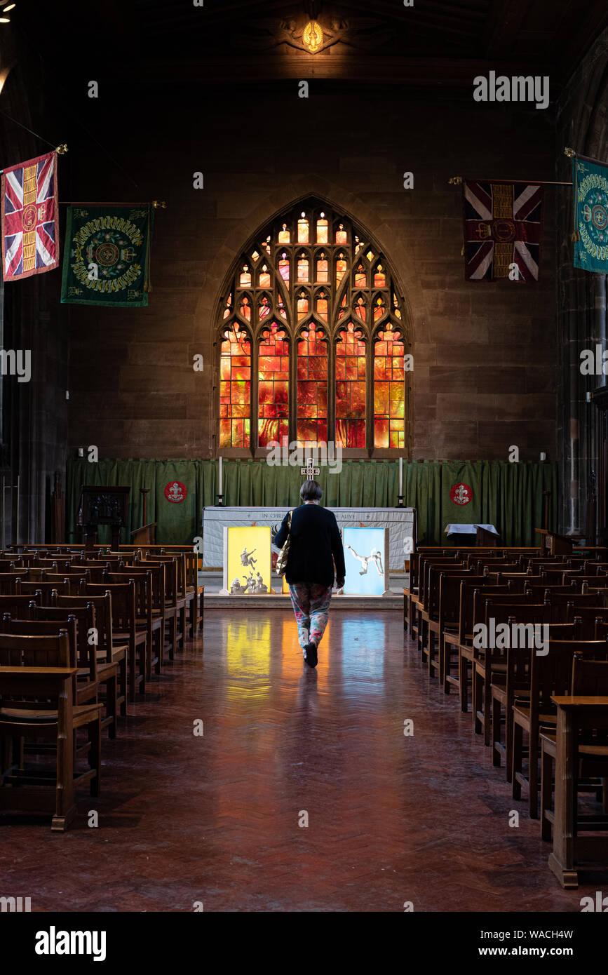 Manchester, United Kingdom – July 16 2019: Senior woman walking in the interior of the famous Catholic Manchester Cathedral with the beautiful stained Stock Photo