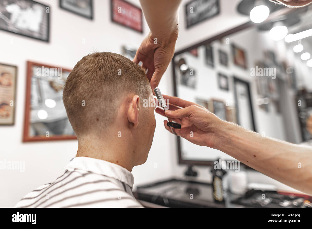 Barber makes a stylish haircut and styling for the client in the beauty salon. Stock Photo