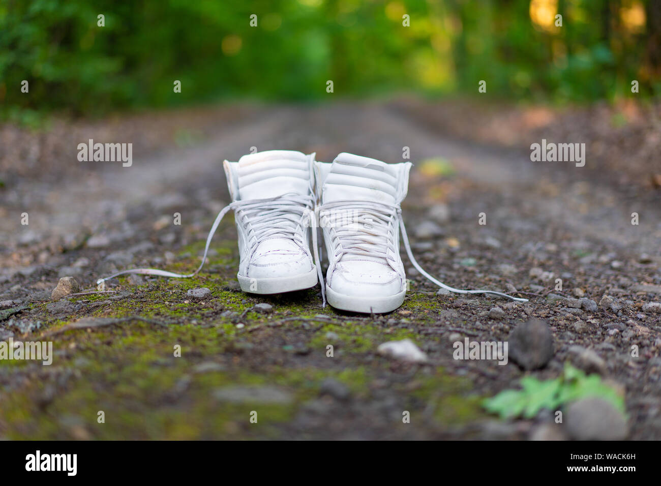 Used White High Sneakers Stand On A Rural Road That Runs In The