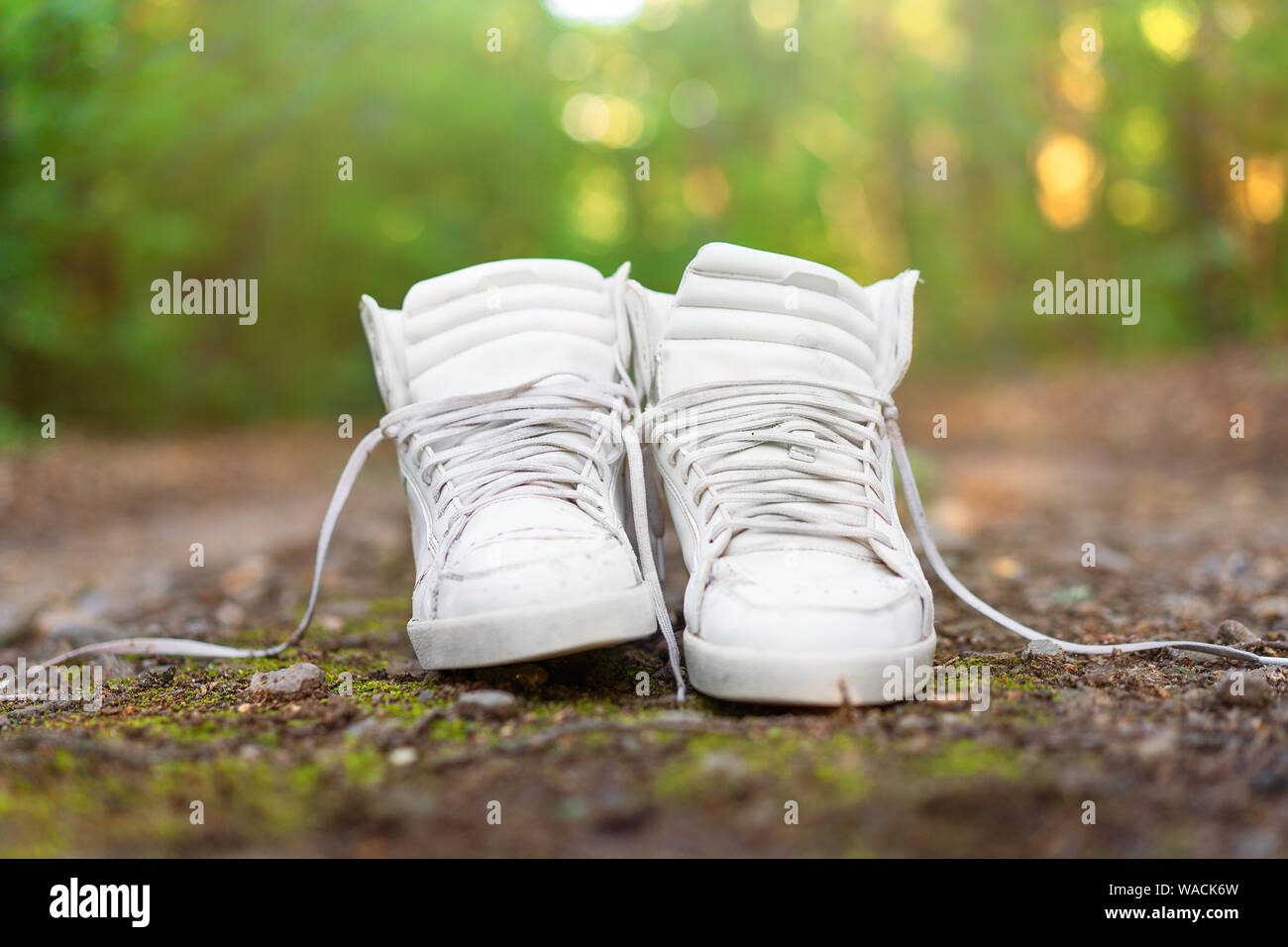 Used White High Sneakers Stand On A Rural Road That Runs In The