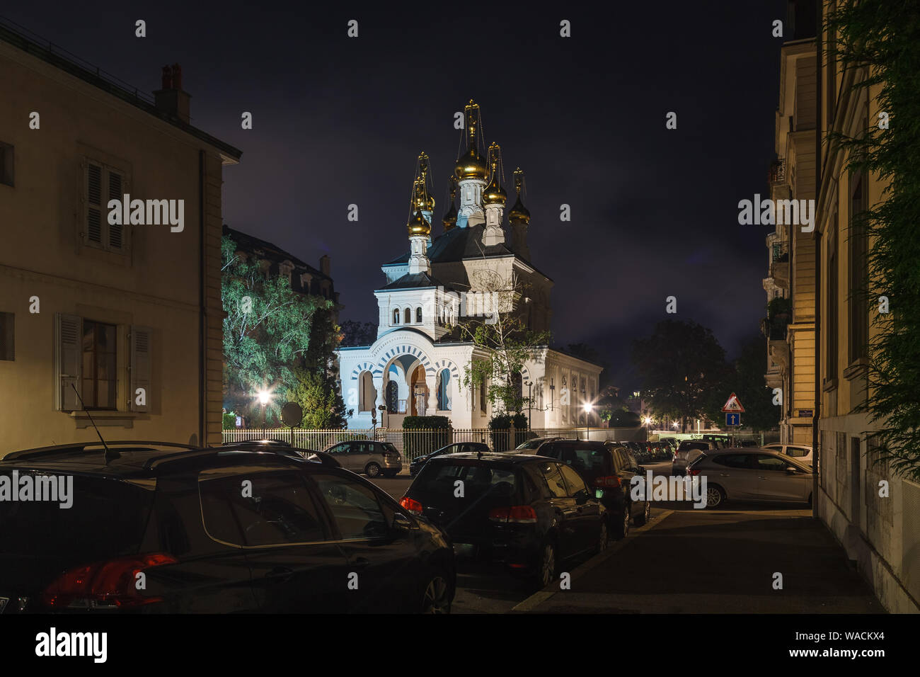 Geneva street with parked cars and Russian orthodox church (Eglise Russe) with golden onion domes at night time, Geneva, Switzerland, Europe Stock Photo