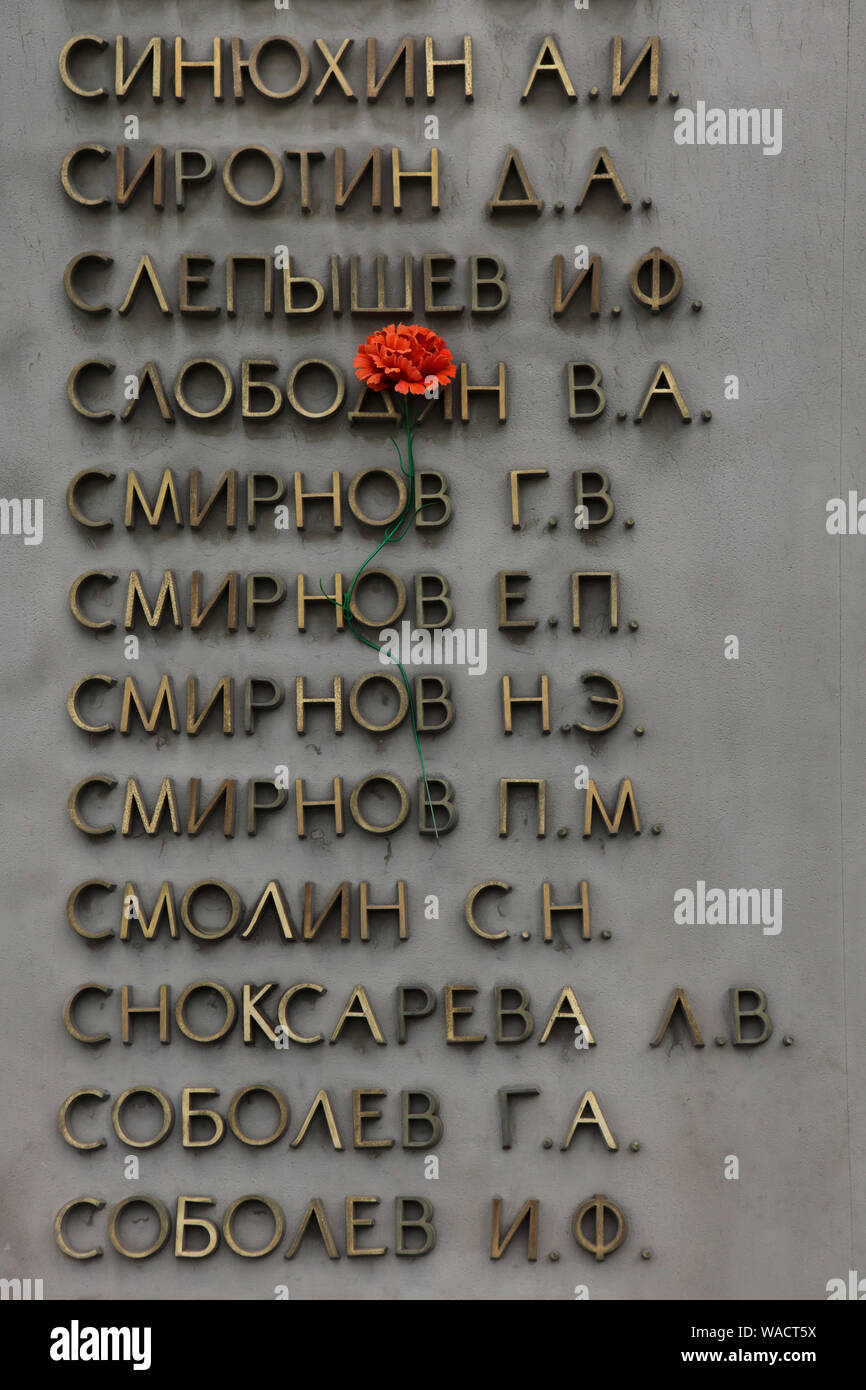 Plastic flower placed between the names of Soviet soldiers on the ground of the memorial to the fallen during World War II at Shirokorechenskoye Cemetery in Yekaterinburg, Russia. Stock Photo